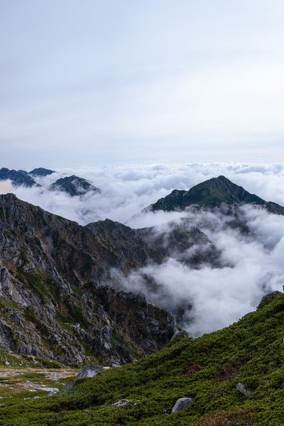 云层上方长满草的山脉中的岩层