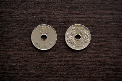 The back and front of a Japanese 50-yen coin.