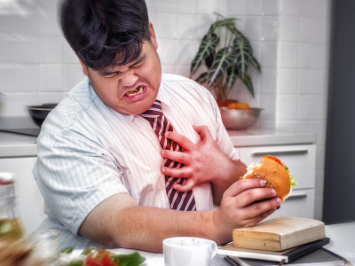 亚洲胖男人吃东西时感到心痛。心脏病发作，胸痛的男人。
