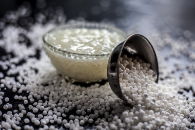 近距离拍摄的sabudana ki kheer在一个玻璃碗连同一些生木薯珍珠和糖铺在表面。