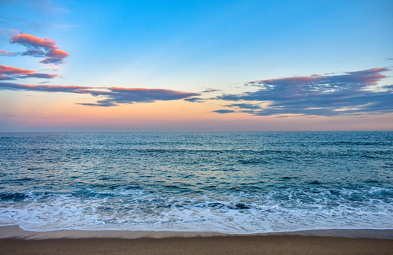 西班牙巴塞罗那，日落时分，美丽的马尔贝拉海滩(Platja de la Mar Bella)