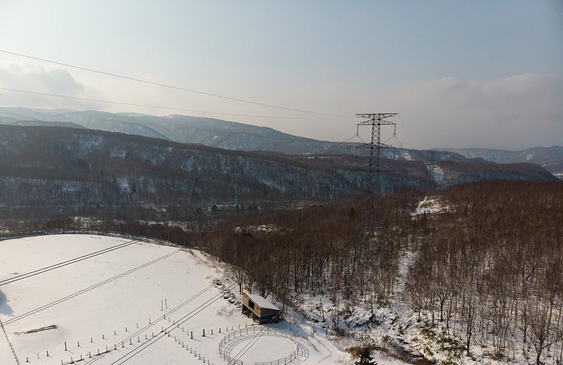 北海道Tokiwa的山坡上，在初冬的时候，空旷的雪覆盖着田野，照片中是电力线