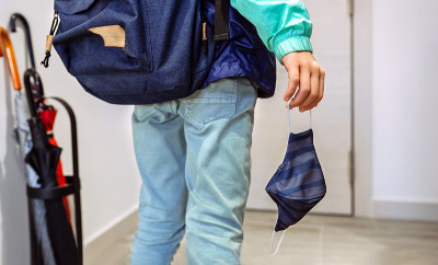 一个陌生的男孩背着背包，手里拿着面具