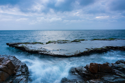 在雨季，海岸上有波浪和青苔的沉积岩海滩