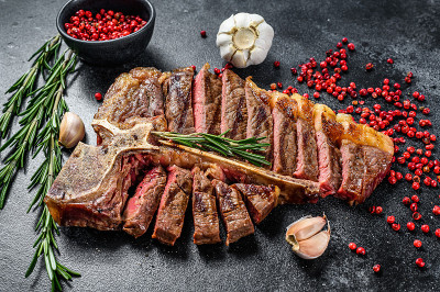 切片烤t骨牛排。煮过的带骨牛肉。黑色背景。俯视图