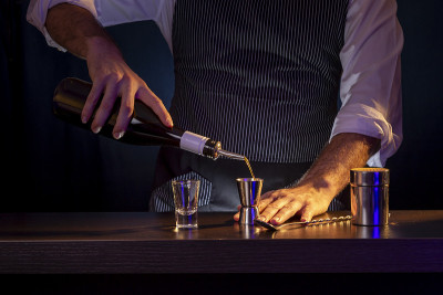 调酒师将鸡尾酒配料倒入量杯