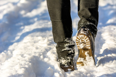 女人穿着雪地靴行走，冬天的女人脚上穿着鞋，腿上穿着牛仔裤