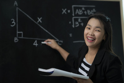 一位亚洲老师在教室里向她的学生解释数学公式