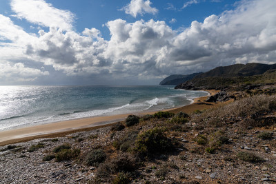 有山脉的岩石海岸，前景是美丽的金色沙滩