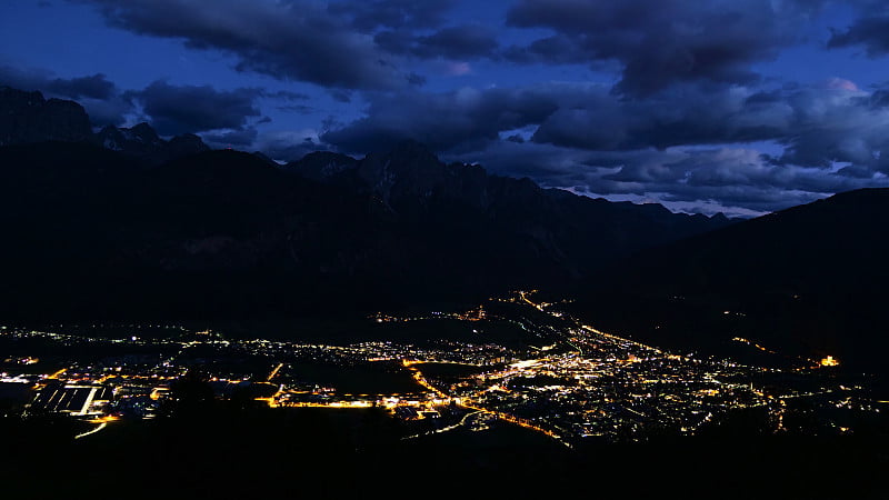 令人惊叹的空中夜景，在蒂罗尔的连茨镇，奥地利山谷和雄伟的阿尔卑斯山脉发光的建筑物。