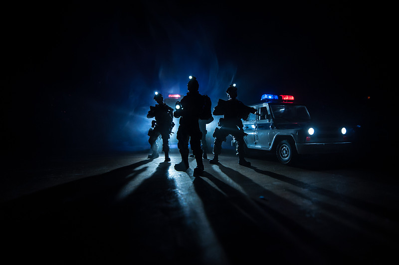 防暴警察发出了准备就绪的信号。政府权力的概念。警方在行动。烟雾在黑暗的背景与灯光。蓝红闪烁的警笛。独