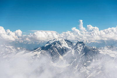 深蓝的天空和云在岩石山峰上覆盖着冰川和雪