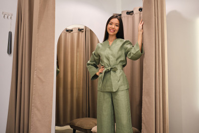 在现代服装店的试衣间里，漂亮微笑的亚洲女孩正愉快地看着镜头，试穿着时髦的西装