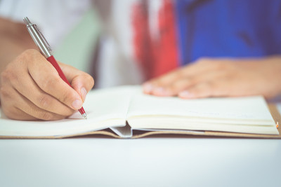 图为一名男学生在家里用智能手机记笔记