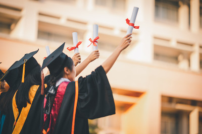 毕业生戴着黑帽子拿着大学毕业证书，向概念教育祝贺。毕业典礼，祝贺大学毕业生。