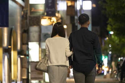 男人和女人手拉手走在市中心晚上的背影