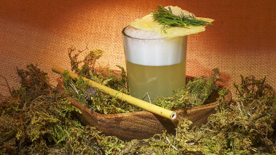 特色私酿鸡尾酒与竹稻草和苔藓在麻袋布的背景。酒精的概念。