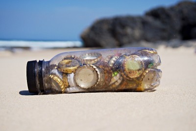 海滩清洁-丢弃的瓶盖收集到一个一次性塑料瓶在海滩