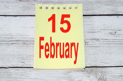 总统日的概念，华盛顿的生日，黄色记事本页上的文字2月15日在一个浅色的木制背景