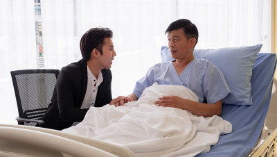 在医院里，儿子拉着父亲的手鼓励他。