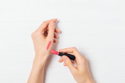 女性的手正在涂抹粉色口红的测试样品