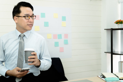 专业的商务人士手持在纸杯玻璃杯中喝新鲜的咖啡早上清爽的咖啡休息前工作会议电脑智能手机手机