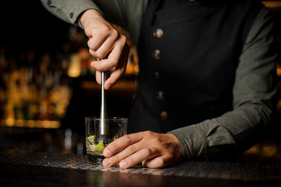 调酒师使用柑橘榨汁机从新鲜的酸橙中榨汁