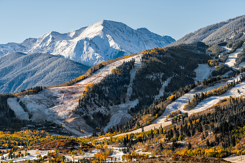 阿斯彭，科罗拉多州酪乳或高地著名的滑雪斜坡山顶在岩石山在阳光明媚的日子与黄色树叶上的雪秋天的树木