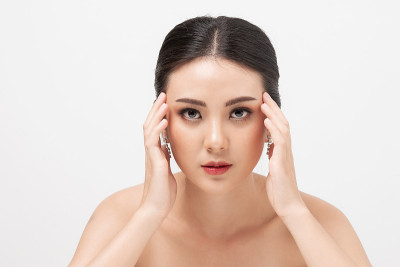 肖像亚洲女性焦虑和手握太阳穴在白色背景。