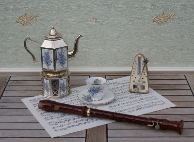 英式茶杯和茶碟，银炉上的镀银茶壶，有花卉装饰，音乐节拍器和乐谱上的长笛