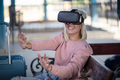 公车站上的女人。年轻女子触摸体验VR头盔。