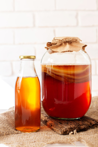 玻璃罐与komucha scoby和一瓶现成的饮料在光线背景