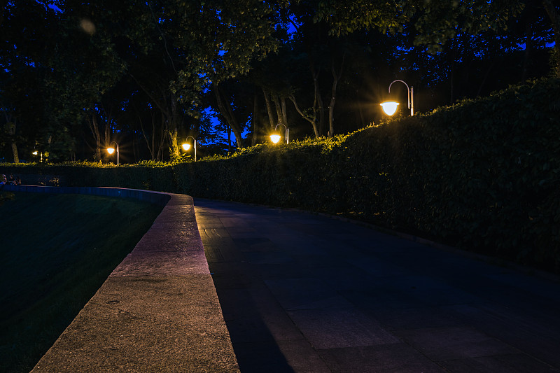 夜晚的瓷砖路，夏天的绿油油的公园里挂着灯笼。夏天晚上公园里的长椅。用灯笼照亮公园的道路。永荣公园。乌