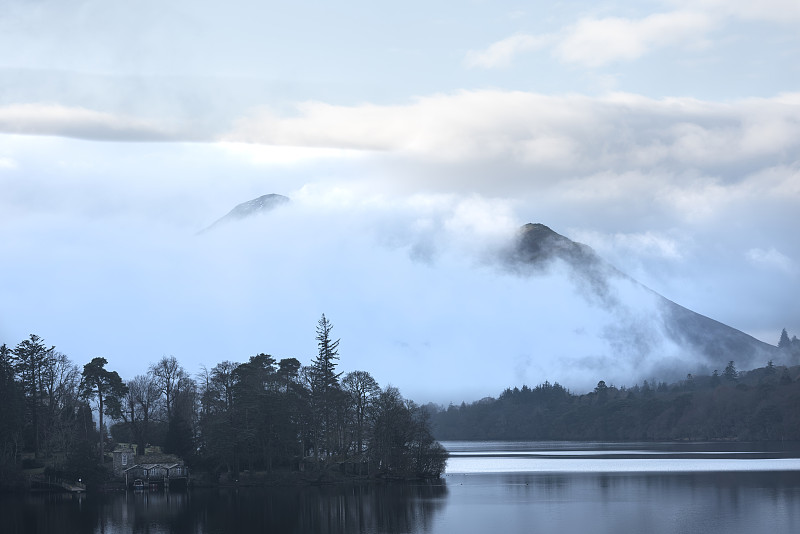 这是一幅引人注目的景观图片，从Derwentwater湖区望向Catbells雪山，浓雾在山谷中翻滚