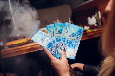 新的俄罗斯纸币面额为2000卢布，男性手中的特写，灰色背景，俯视图