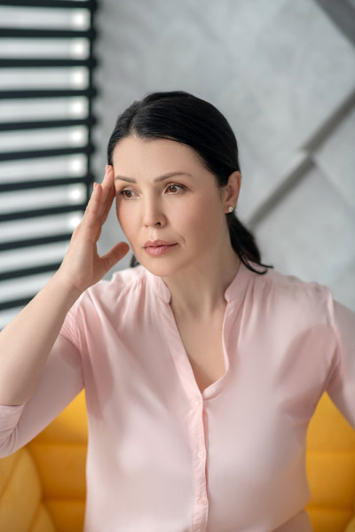 穿着粉红色衬衫的漂亮成年女人往一边看。