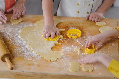 Children's hands making biscuits with help of cutt