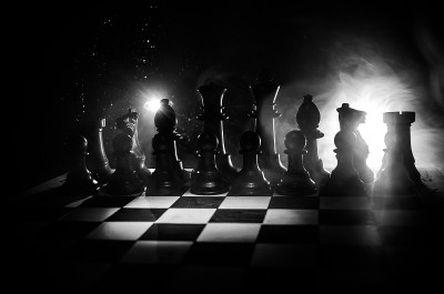 棋牌游戏的经营理念和竞争理念以及战略理念。象棋人物在烟雾缭绕的黑暗背景上。