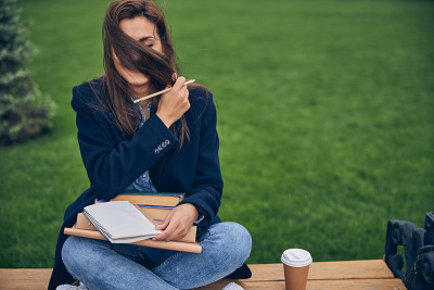 年轻的女士在外面喝着咖啡享受美好的天气