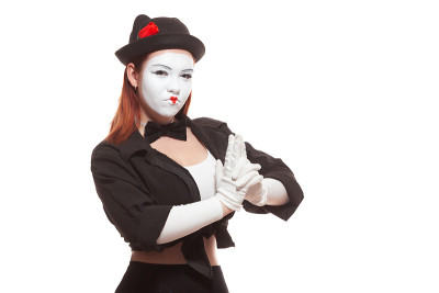 一个女哑剧演员的肖像表演，孤立在白色的背景。哑剧演员假装拿着枪准备射击