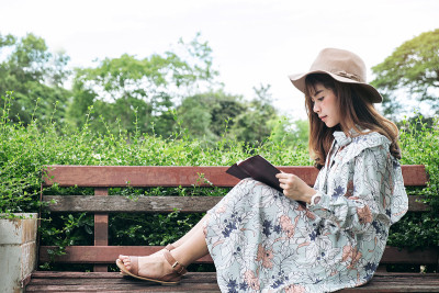 迷人的亚洲女人阅读和放松在公园