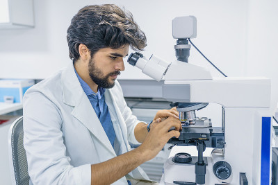 在实验室用显微镜工作的专注的科学家
