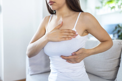 一个年轻的白人妇女自己摸她的乳房说她很担心乳腺癌。保健和乳腺癌概念