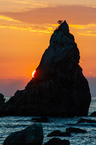 太阳从海岸上一块巨石的另一边升起