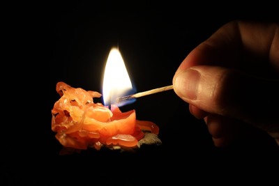 在黑暗中燃烧的蜡烛点亮了一根火柴
