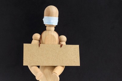 带医用口罩的木制娃娃或人体模型上有文字空间的硬纸板。反种族主义的概念、社会距离、隔离、新冠肺炎周围的