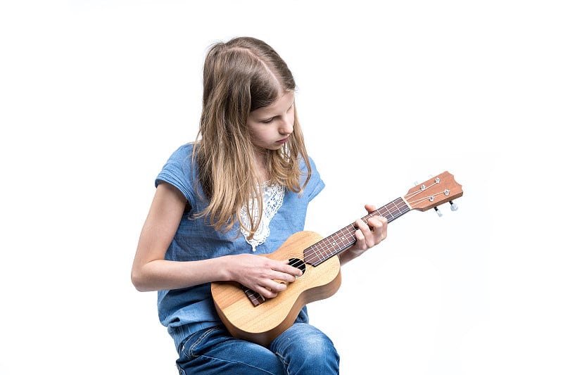 Young, blond girl in blue T-shirt is playing music