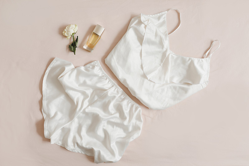 女性丝绸内衣米色背景俯视图，flatlay。女性蕾丝睡衣衣服