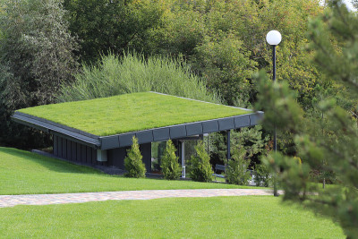 A small modern building in a park with a grassy la