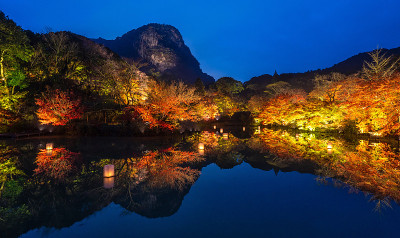美丽的日本花园，名为mifuyama Rakuen在秋天的夜景枫叶和湖反射。